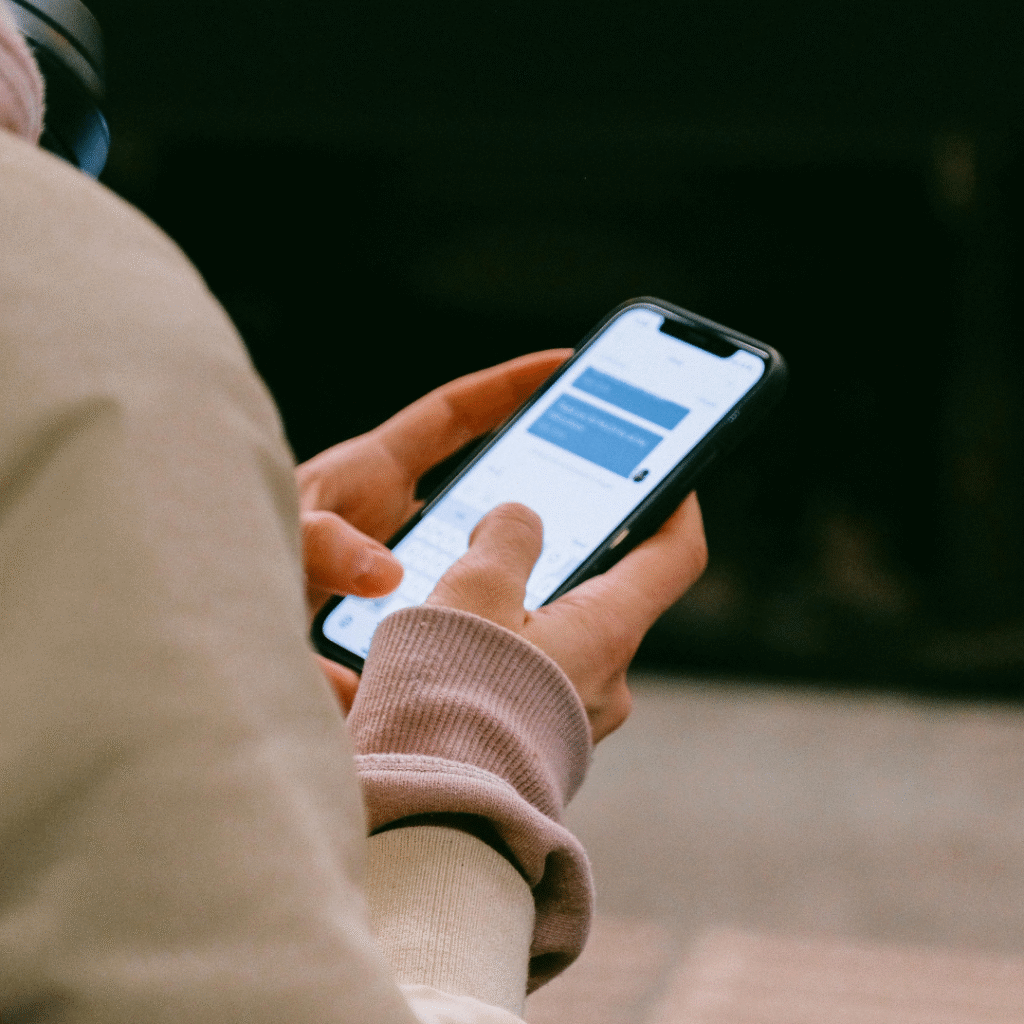 Client texting on smartphone to book an appointment using a tattoo booking app powered by AI