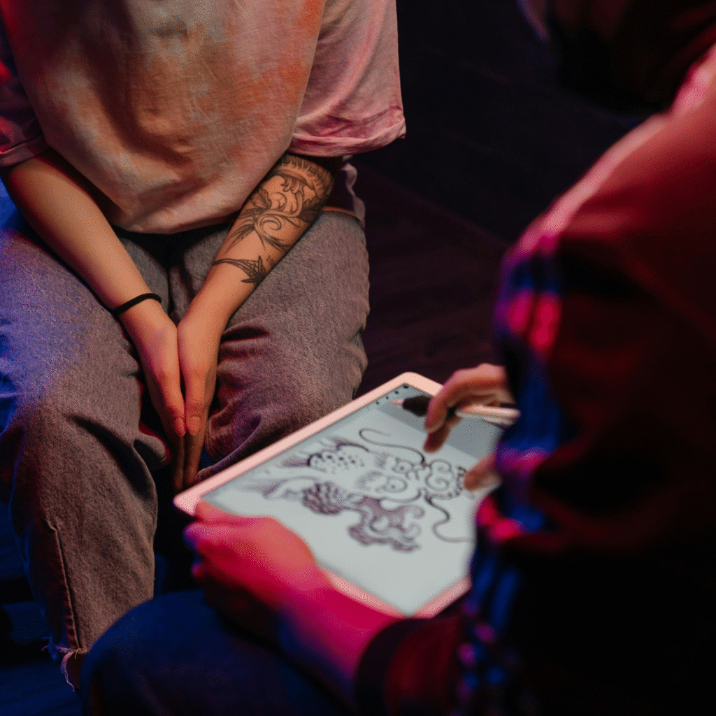 iPad showing digital stencil design next to a tattoo booking app interface