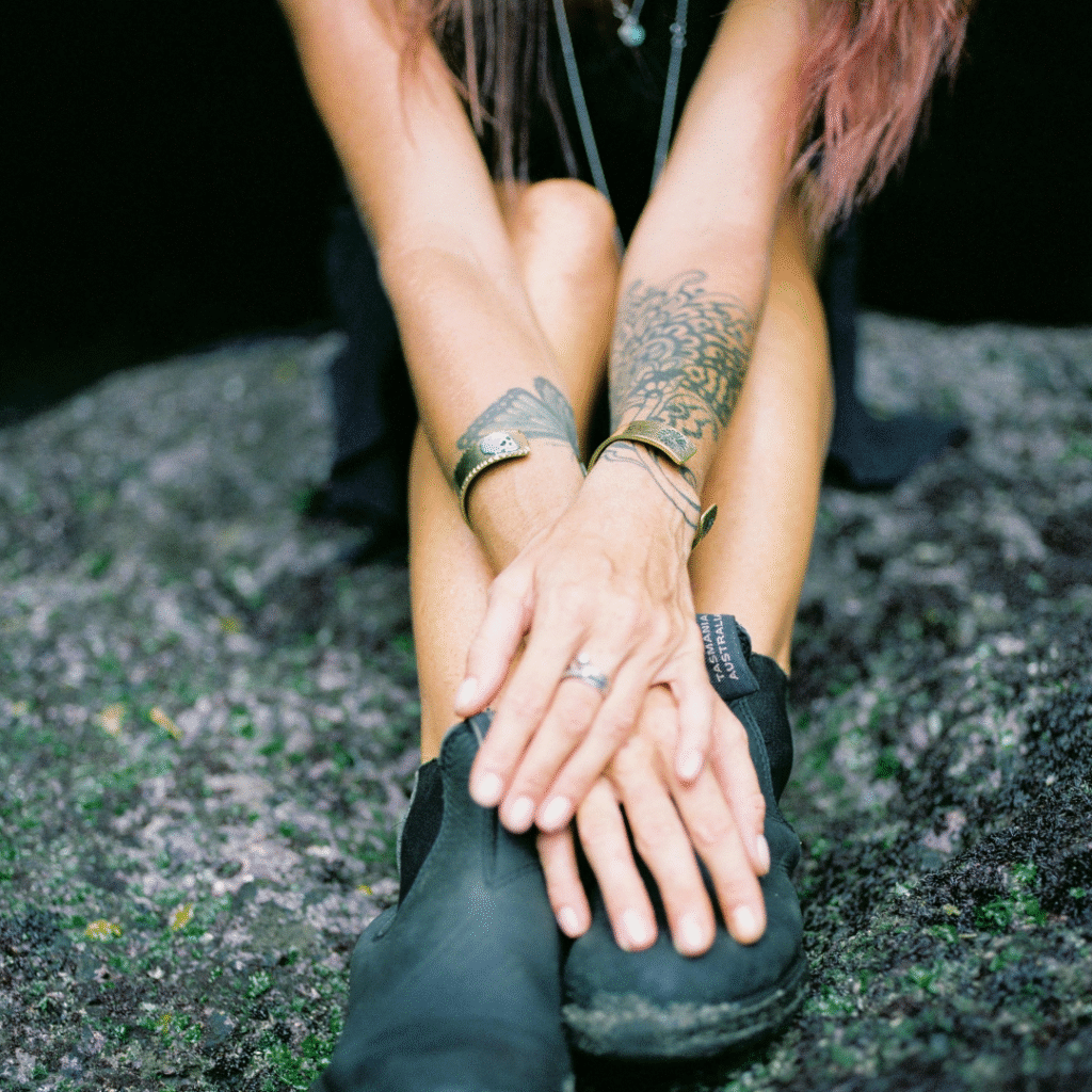 Tattoo travel app user sitting outdoors with visible forearm tattoo, symbolizing freedom and flexibility for traveling tattoo artists.
