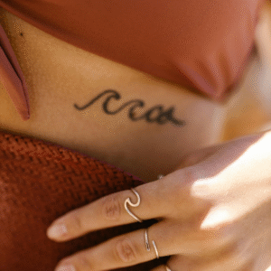 Minimalist wave tattoo on ribcage with matching wave ring