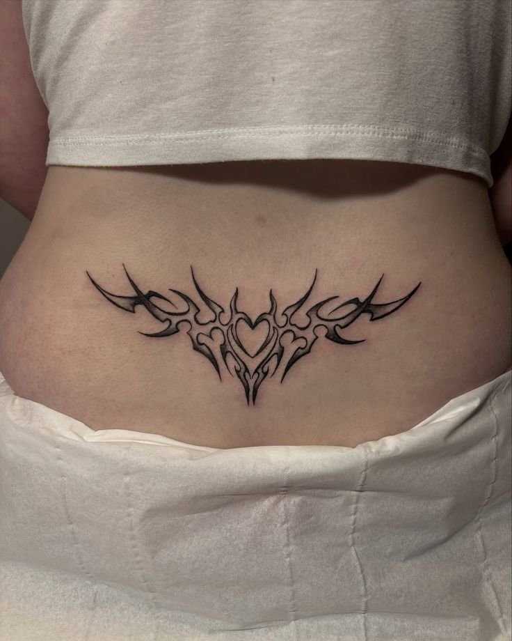 Lower Back Tribal Tattoo – Bold Heart & Flame Design Lower back tribal tattoo with bold black heart and flame-inspired design
