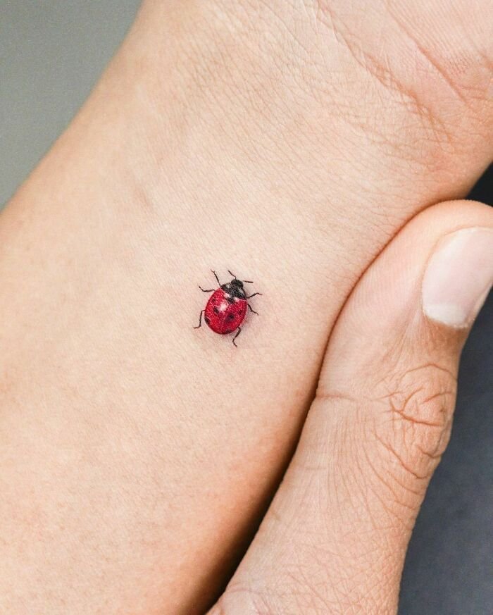 Tiny colorful ladybug tattoo on wrist – book tattoo appointment online easily