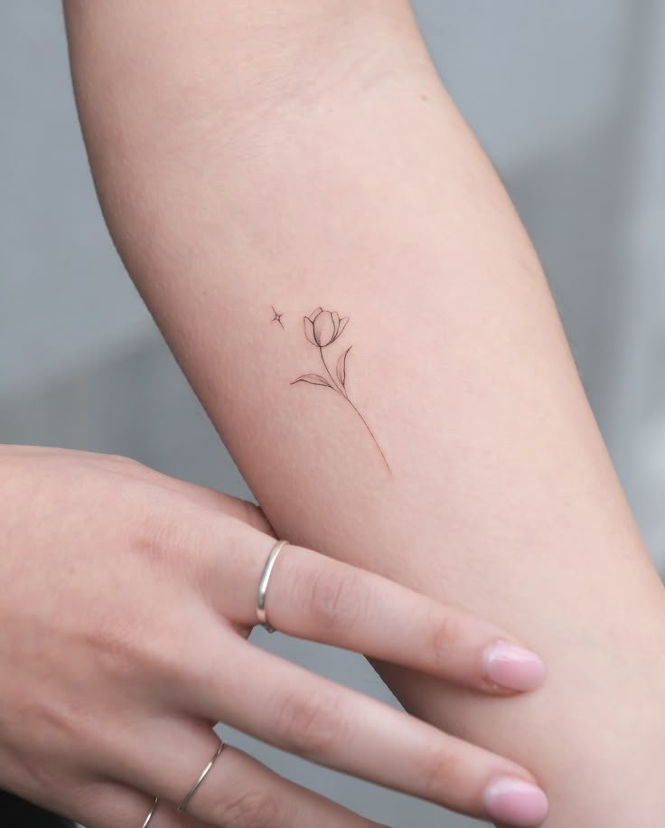 Minimalist Flower Tattoo – Fine Line Floral Design Tiny minimalist flower tattoo on forearm with fine line details