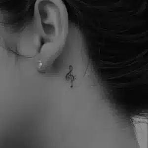 tiny treble clef music-inspired tattoo behind ear
