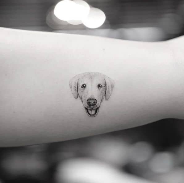 tiny minimalist labrador portrait tattoo with clean black lines on forearm