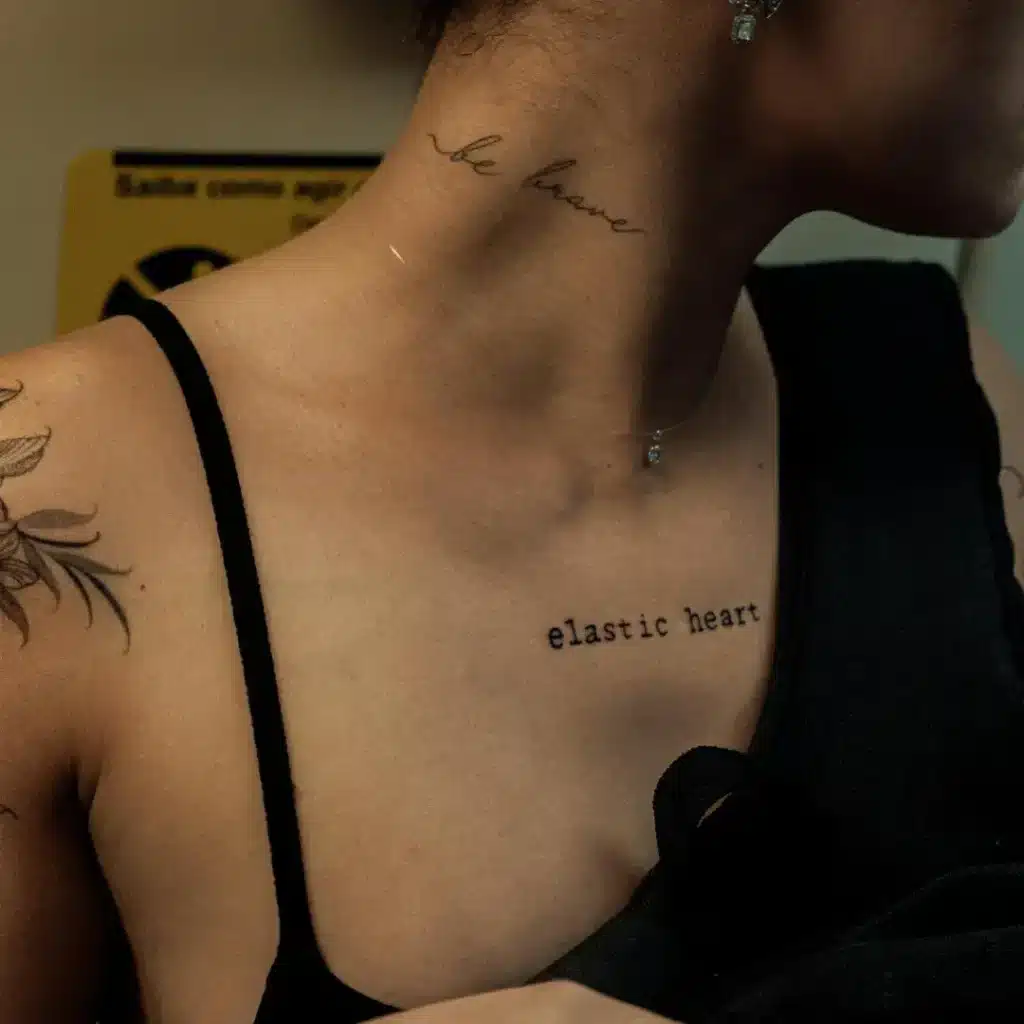 fine-line script tattoo on neck with minimalist floral ink on shoulder