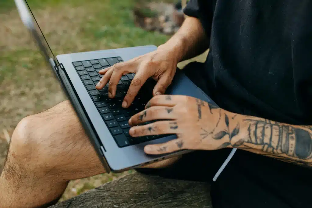 Tattoo artist using laptop to explore the best tattoo scheduling app for studio bookings