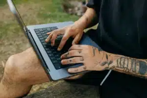 Tattoo artist using laptop to explore the best tattoo scheduling app for studio bookings