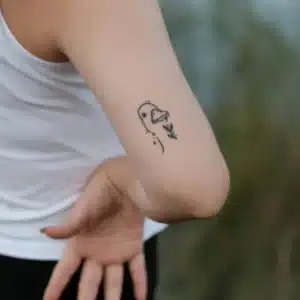 Minimal line-art duck tattoo on the back of a person’s arm.