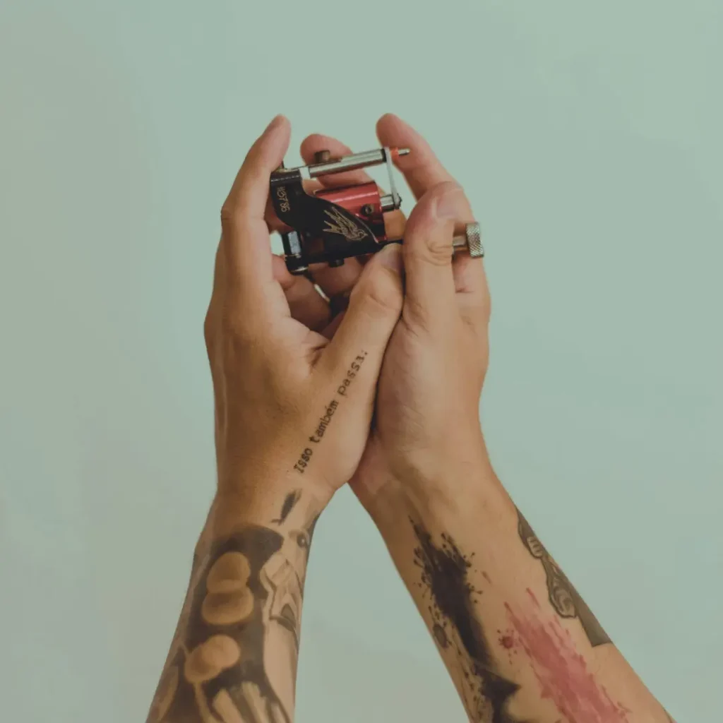 Tattoo artist holding tattoo machine representing modern communication and tattoo booking by text